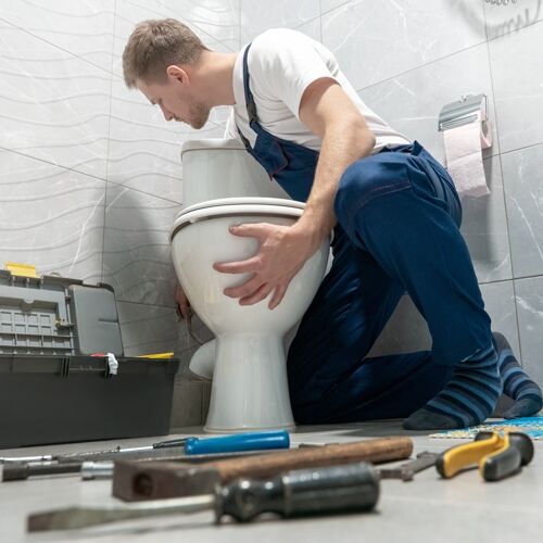 man plumber in uniform installing toilet bowl using instrument kit professional repair service Installing a new toilet